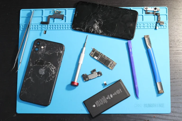 iPhone à la vitre arrière brisée, démonté au milieu des outils de réparation